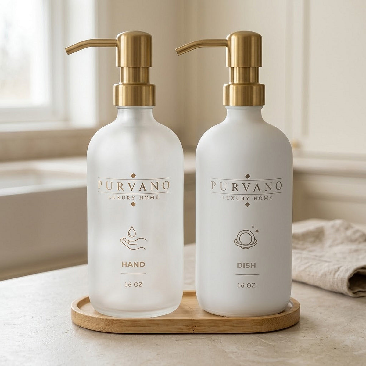 PURVANO frosted and white soap dispenser duo on a stone kitchen counter beside folded linen in soft daylight